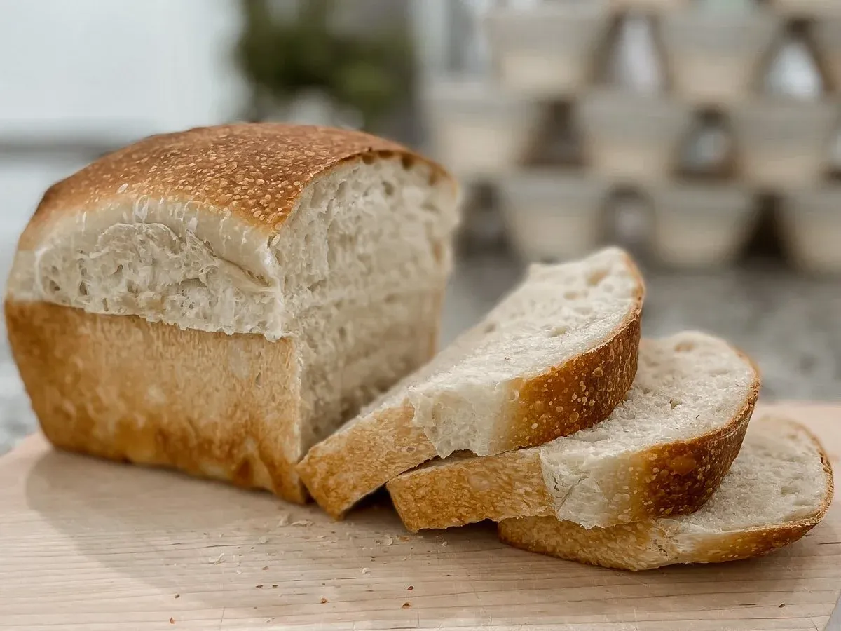 Freshly sliced organic sourdough loaf on a wooden board, showing a soft open crumb